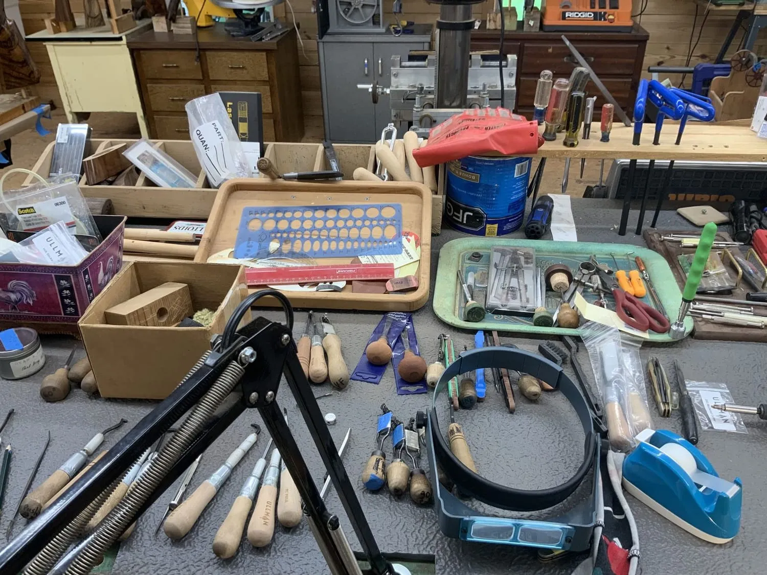 Checkering cradles, files and wooden-handled cutters laid out on the bench beside a magnifier visor